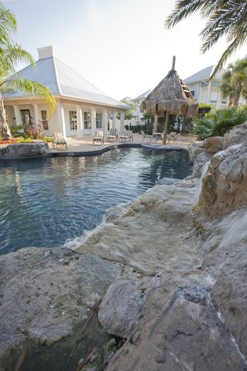 a pool with a waterfall and a house in the background